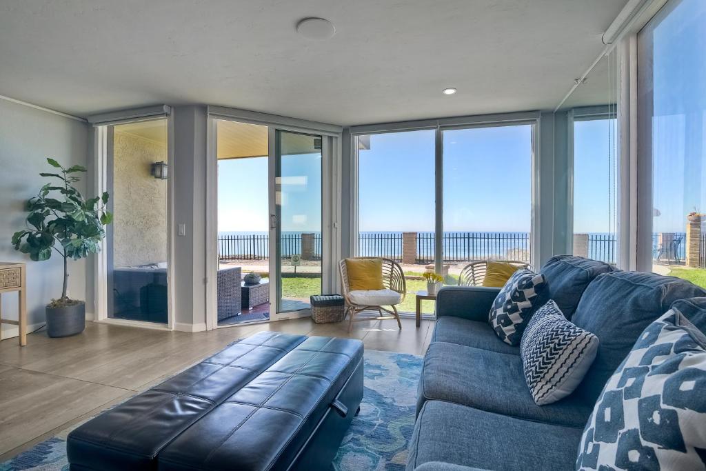 a living room with a blue couch and large windows at Oceanfront Condo, Hot Tub, Heated Pool, Beach Access, Beach Gear in Solana Beach
