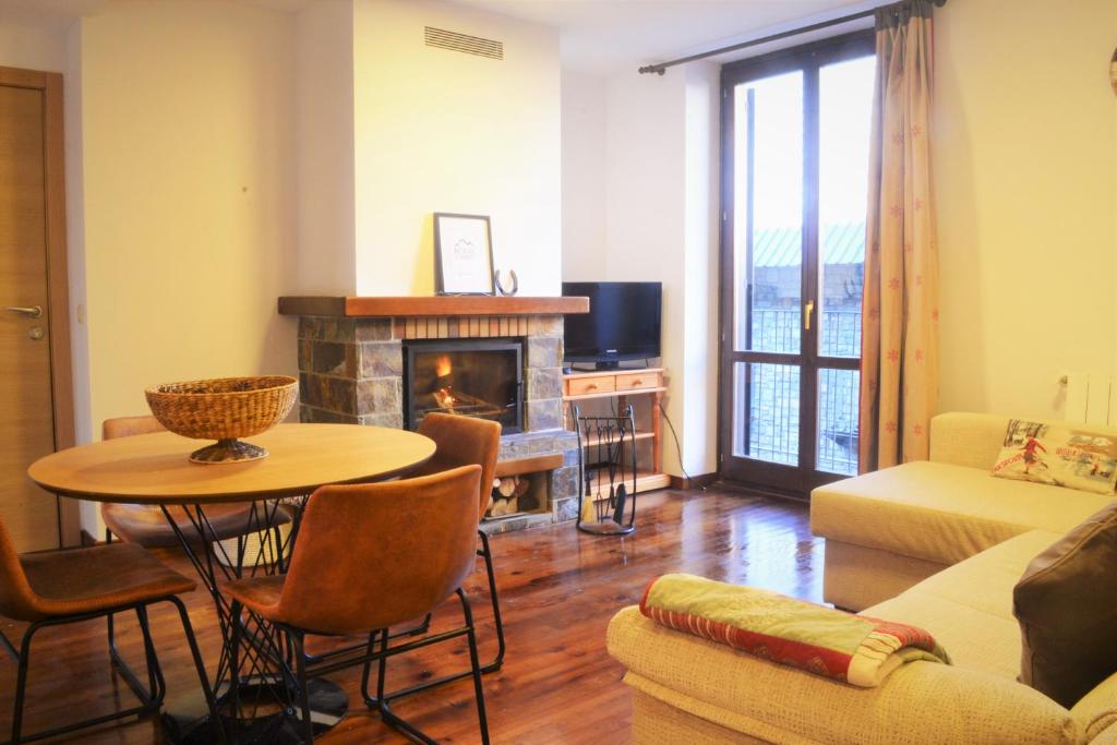 sala de estar con mesa y chimenea en Apartament acollidor amb una gran llar de foc by RURAL D'ÀNEU, en Esterri d'Àneu