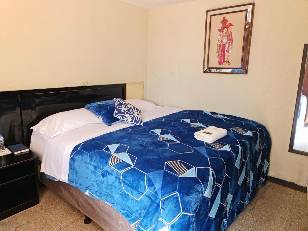 1 dormitorio con 1 cama con edredón azul y blanco en Hotel Kasa Kamelot Las Rosas, en Quetzaltenango