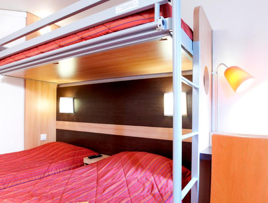 ein Schlafzimmer mit einem Etagenbett mit roter Bettwäsche in der Unterkunft Premiere Classe Valenciennes Sud - Rouvignies in Valenciennes