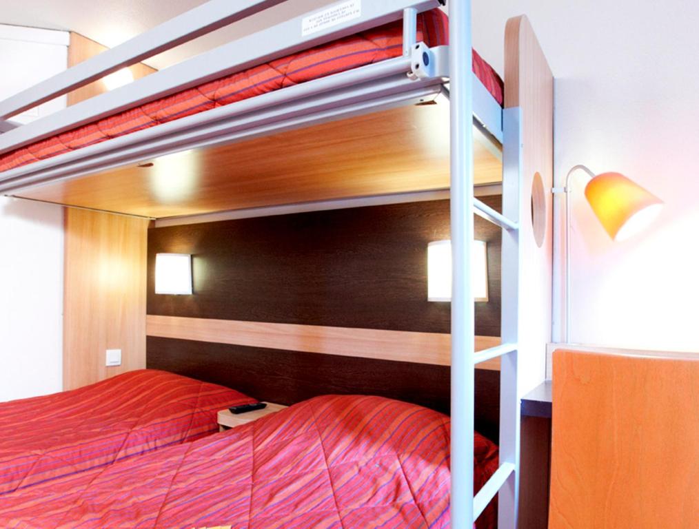 a bedroom with a bunk bed with red sheets at Premiere Classe Valenciennes Sud - Rouvignies in Valenciennes
