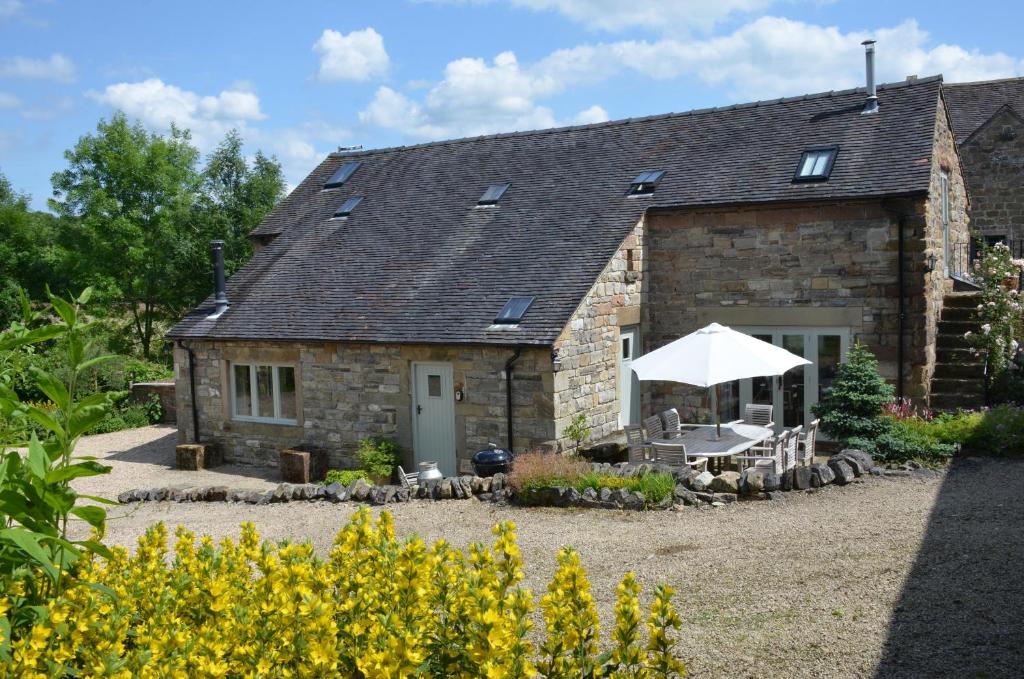 a stone cottage with a table and a white umbrella at Green Farm Stables in Ashbourne