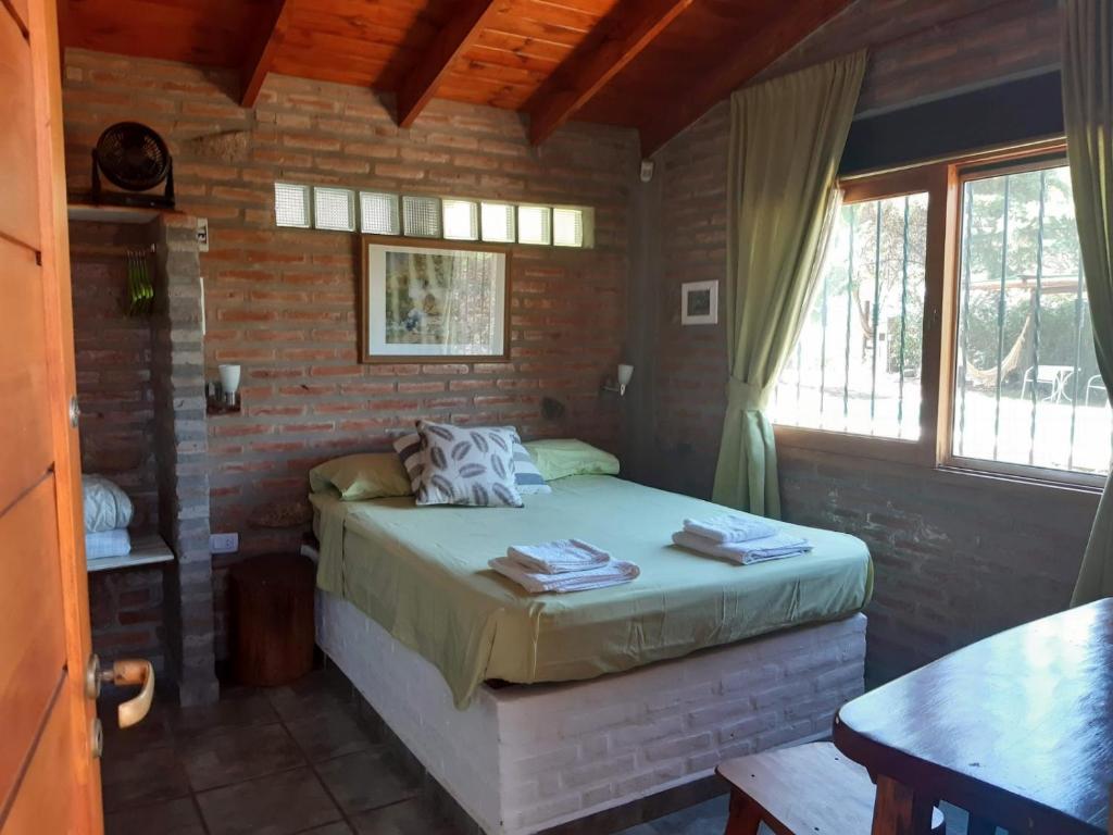 a bedroom with a bed in a brick wall at Cabañas Farah Estancia Vieja ideal para 2 a 3 huéspedes in Villa Carlos Paz