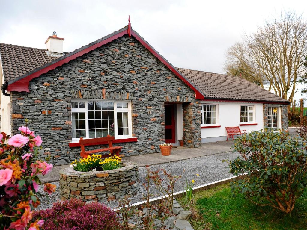 una casa de piedra con un banco delante en The Lodge, en Beaufort