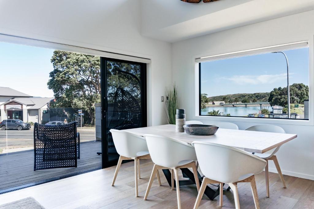 a dining room with a table and chairs and a large window at Harbourview Haven in Raglan