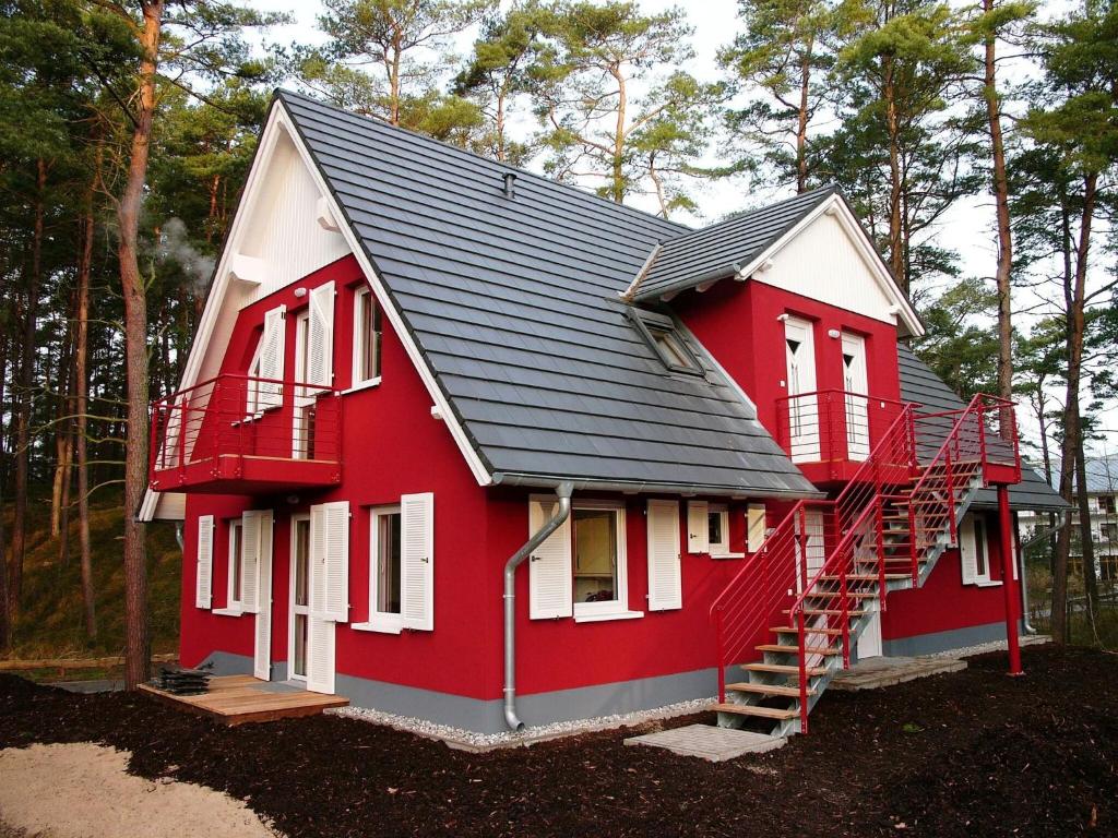 een rood-wit huis met een metalen dak bij Apartment house, Trassenheide in Trassenheide