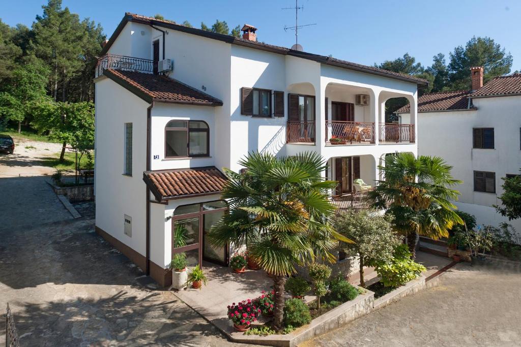 a white house with a palm tree in front of it at Apartments Prekalj in Poreč