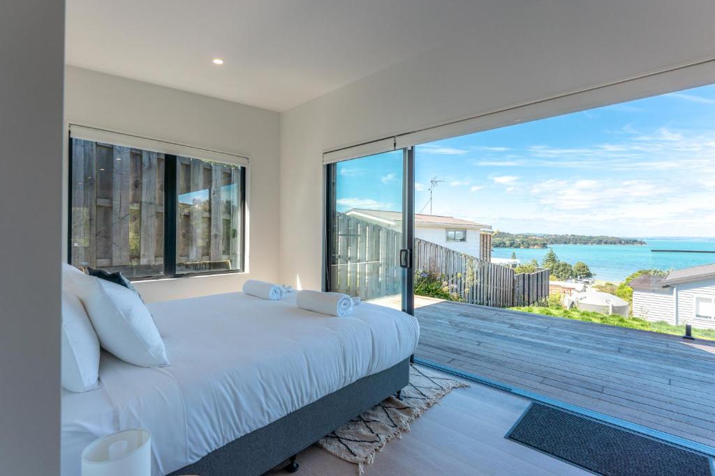 a bedroom with a bed and a large window at Marama Cottages with ocean views in Oneroa