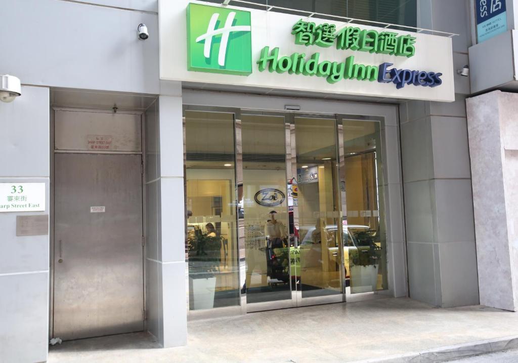 une entrée à un bâtiment avec un panneau sur celui-ci dans l'établissement Holiday Inn Express Hong Kong Causeway Bay, an IHG Hotel, à Hong Kong