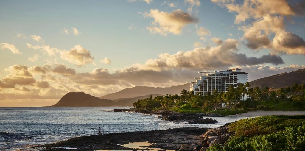 a building on a beach with the ocean at Four Seasons Resort Oahu at Ko Olina in Kapolei