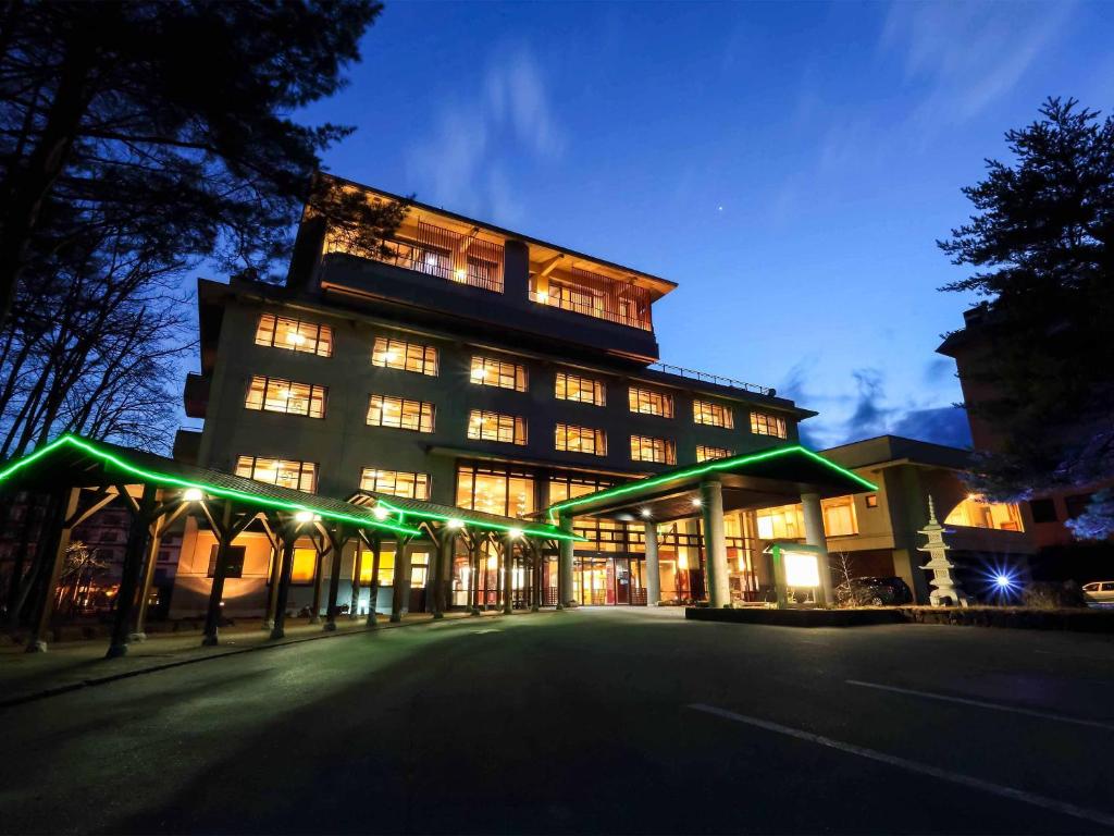 ein großes Gebäude mit grüner Beleuchtung davor in der Unterkunft Kurobe Sunvalley Hotel in Omachi