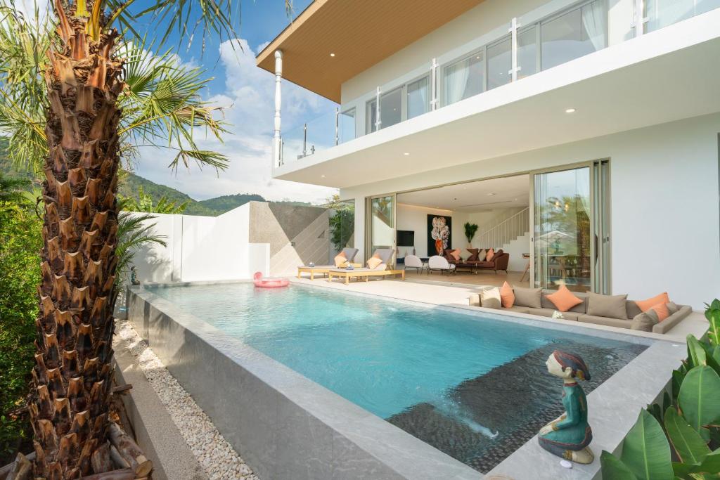 a villa with a swimming pool in front of a house at Capucine Villas in Kamala Beach