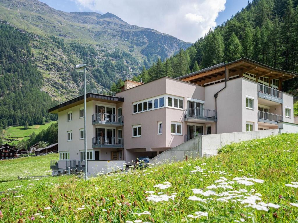 a building on a hill with a field and flowers at Holiday apartment in Zwieselstein near S lden in Sölden