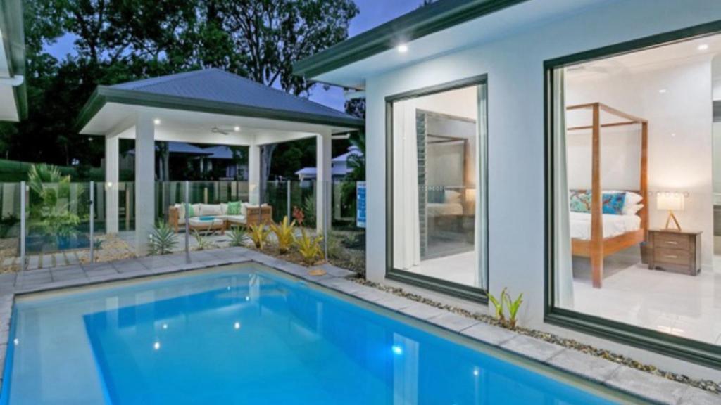 a swimming pool in front of a house at Castaways - Palm Cove in Palm Cove