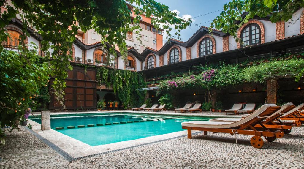 a swimming pool with lounge chairs next to a building at Hotel Restaurant Bujtina e Gjelit in Tirana