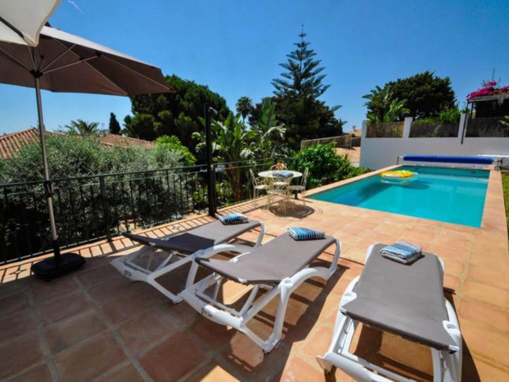 2 sillas y sombrilla junto a la piscina en Belvilla by OYO Casa Amarilla Blanca, en Salobreña