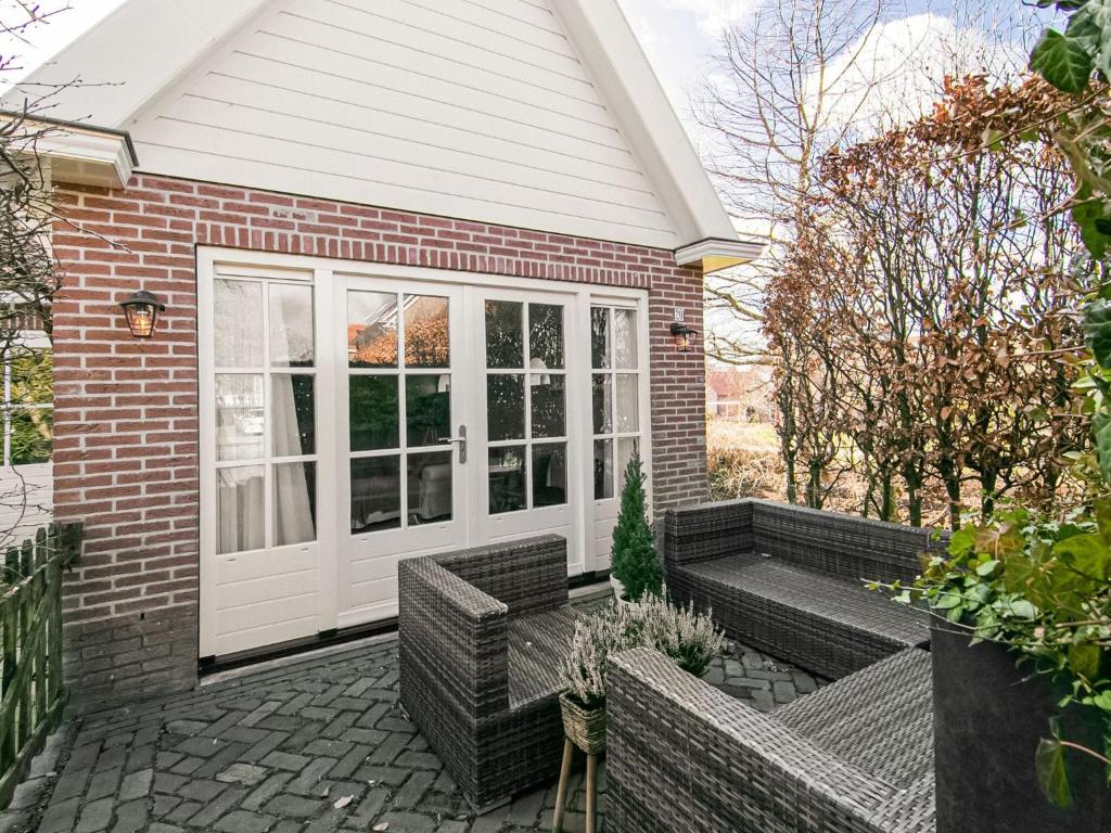 Cette maison en briques dispose d'une terrasse avec des chaises en osier. dans l'établissement Appealing Holiday Home in Medemblik with Garden, à Medemblik