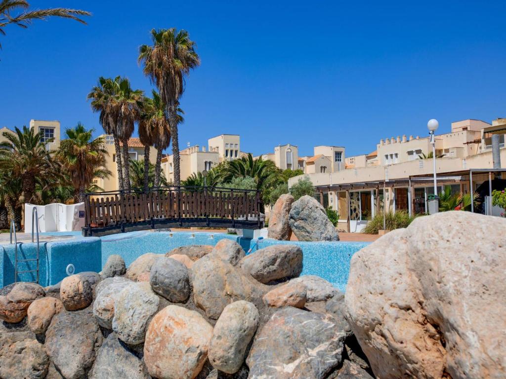 una piscina con rocas frente a un complejo en Lovely Apartment in Andaluc a near Seabeach, en Las Salinas