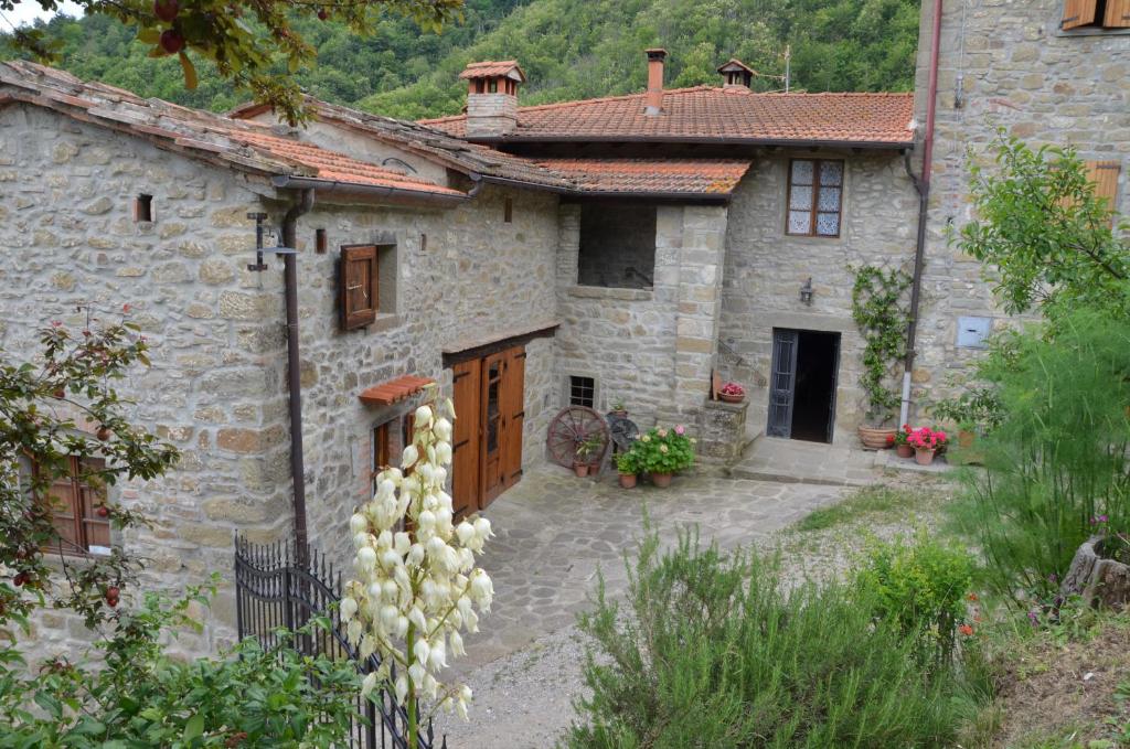 una antigua casa de piedra con un jardín delante de ella en Agriturismo Podere Fiume, en Pratovecchio