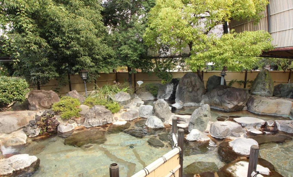 un estanque en un jardín con rocas y árboles en Hotel Hatta, en Fuefuki
