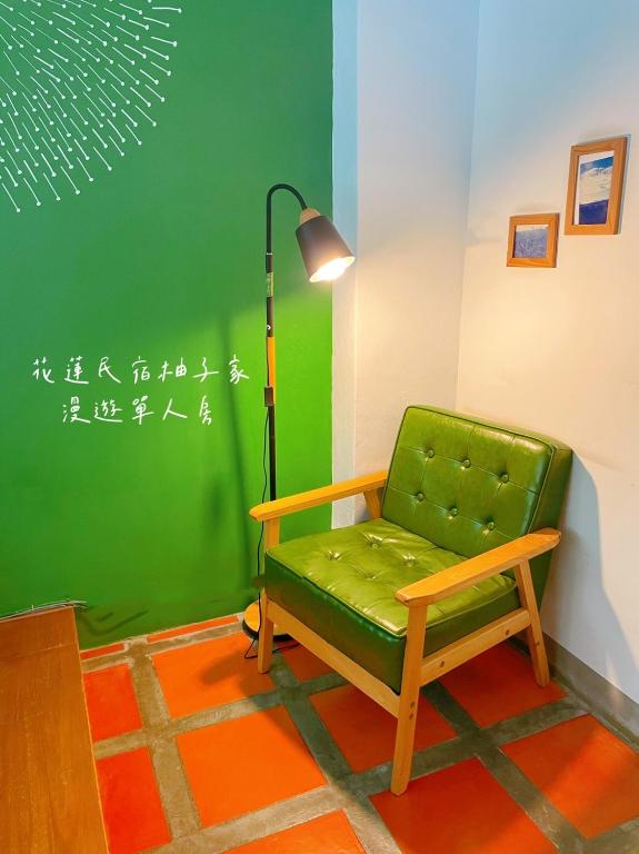 a green chair in a room with a green wall at Yuzi Homestay in Hualien City