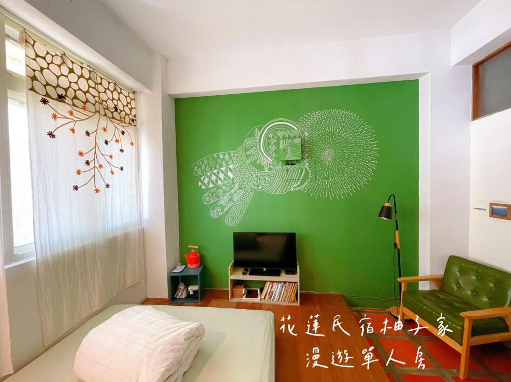 a living room with a green wall and a couch at Yuzi Homestay in Hualien City