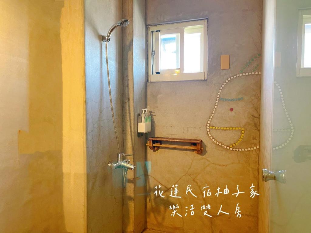 a shower in a bathroom with writing on the wall at Yuzi Homestay in Hualien City