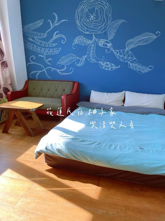 a bedroom with a blue wall with a bed and a table at Yuzi Homestay in Hualien City