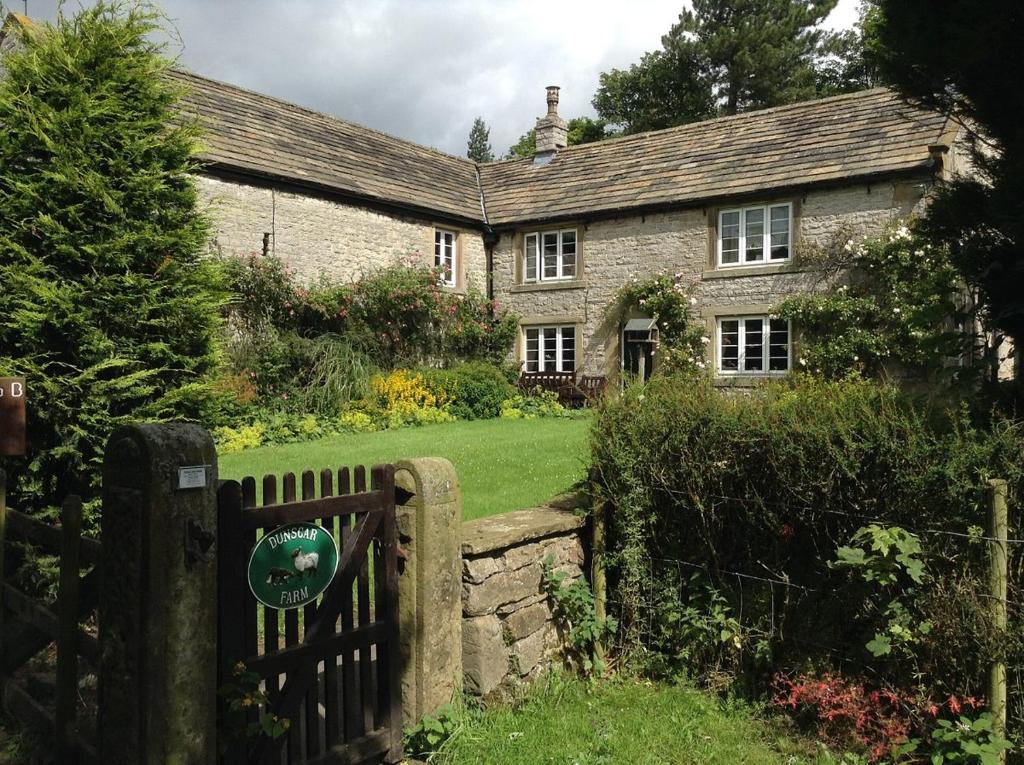 una vieja casa de piedra con una puerta y una valla en Dunscar Farm Bed & Breakfast, en Castleton