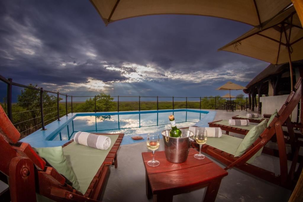 a pool with a table and glasses of wine at Uukwaluudhi Safari Lodge in Okahao