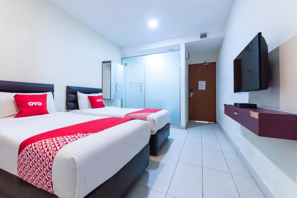 a hotel room with two beds and a flat screen tv at Super OYO 90385 H3 Hotel in Yong Peng
