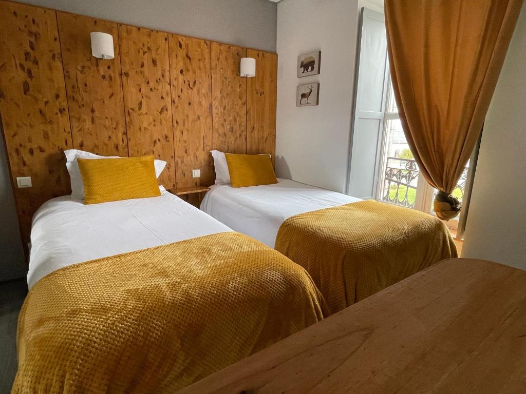 a hotel room with two beds and a window at Le Central Hôtel-Bar in Oloron-Sainte-Marie