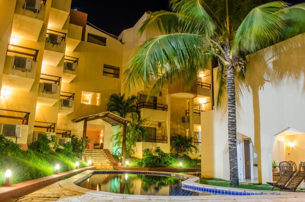 a hotel with a palm tree in front of a building at Hotel Palmanova in Maceió