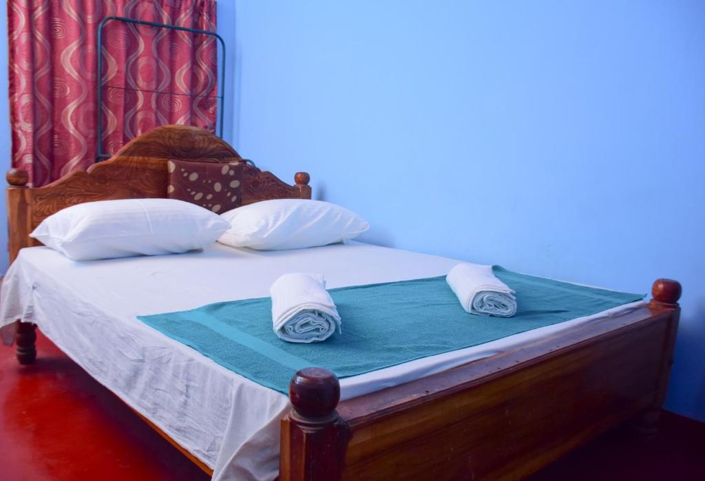 1 cama con marco de madera y toallas en Relax Guest House Dambulla en Dambulla