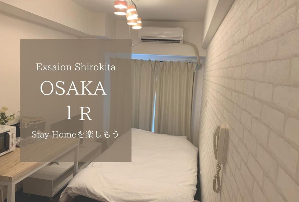 Kleines Zimmer mit einem Bett und einer Wand in der Unterkunft Exsaison Shirokita 705 in Osaka