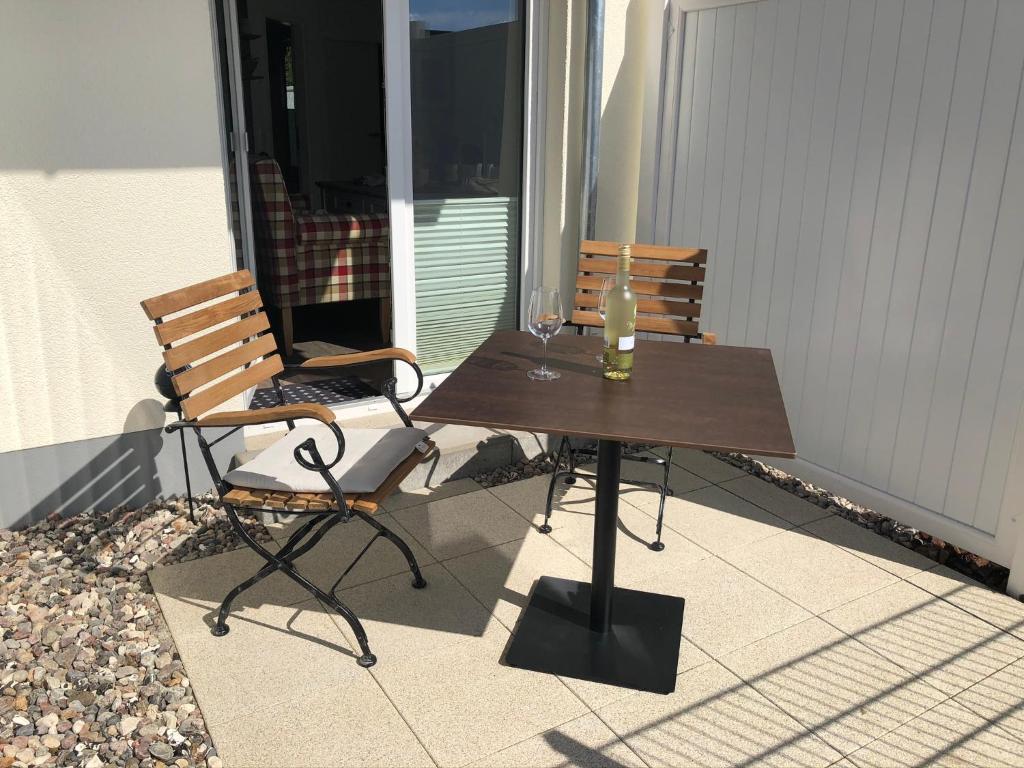 - Balcón con mesa y 2 sillas y copa de vino en Lieblingszeit im Küstenwald Graal-Müritz, en Gelbensande