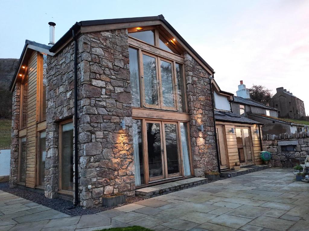 a stone house with large windows on a patio at Ty Gwyn Cottage in Llysfaen