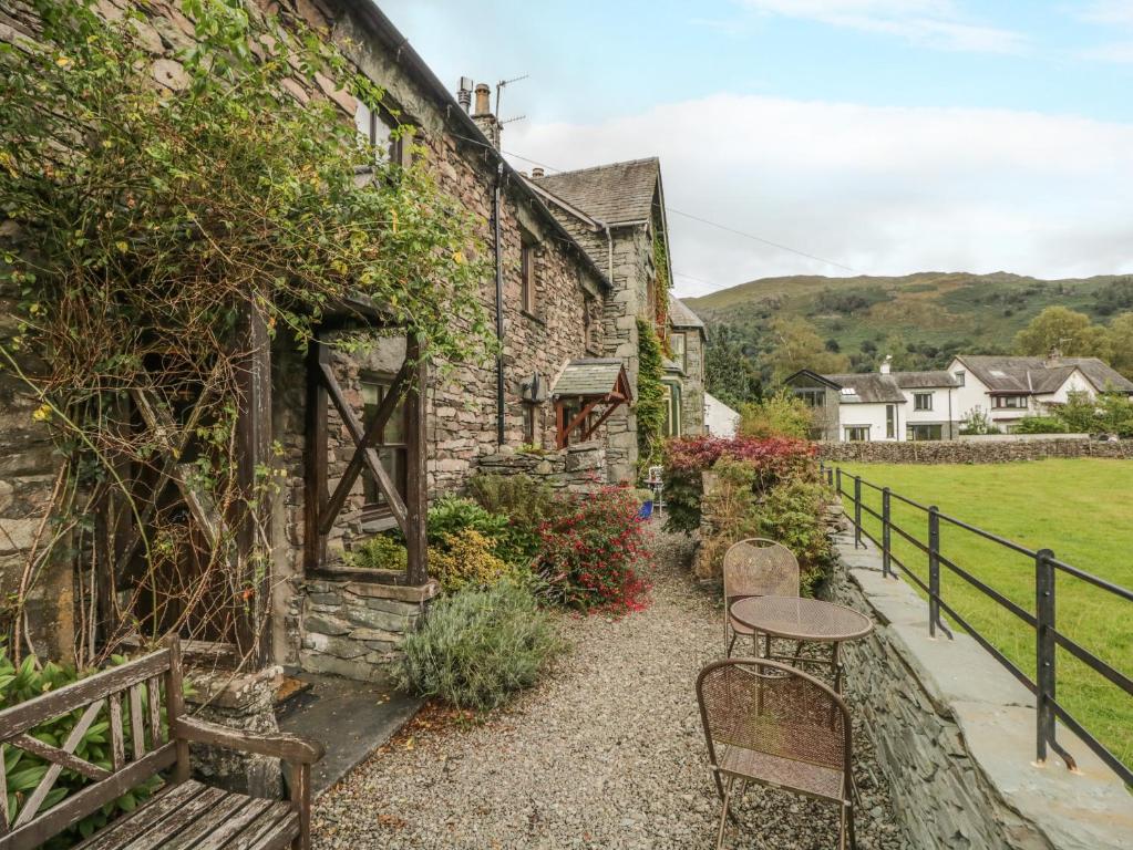 ein Steinhaus mit einem Tisch und Stühlen im Freien in der Unterkunft Tanner Croft Cottage in Ambleside