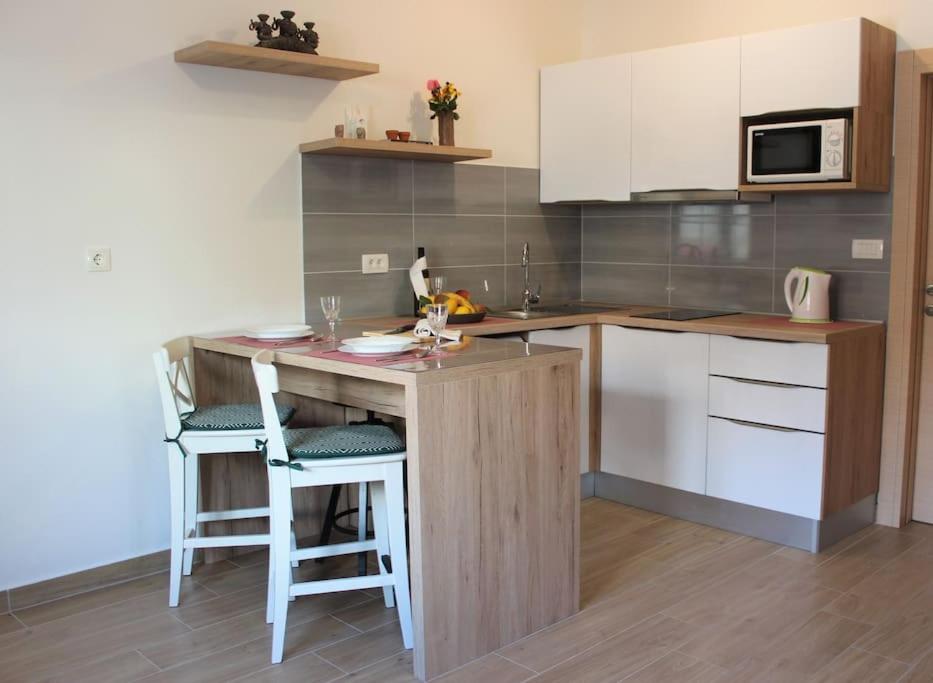 a kitchen with a counter with stools and a table at Apartments Piscina-Green in Podstrana