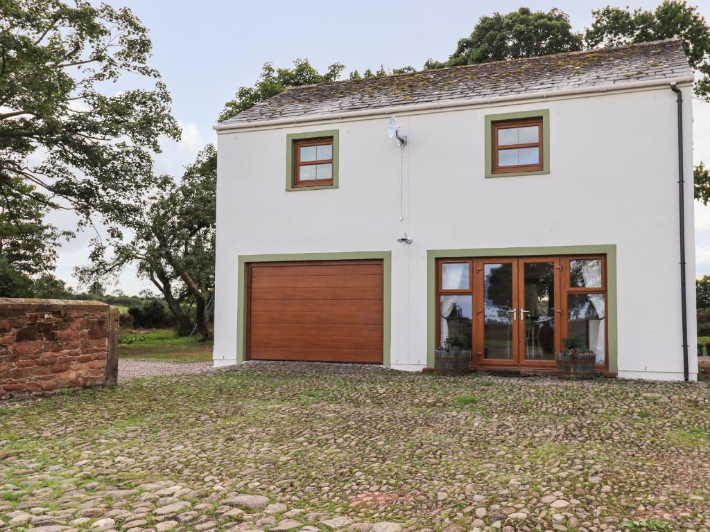 uma casa branca com uma porta de garagem de madeira em Bramblewood Cottage 