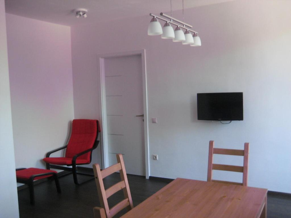 a living room with two chairs and a table and a tv at Platán apartman in Budapest