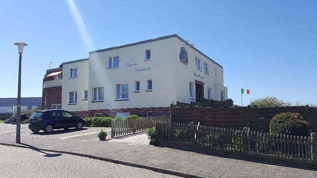 ein weißes Gebäude mit einem davor geparkt in der Unterkunft Hotel Passat in Borkum