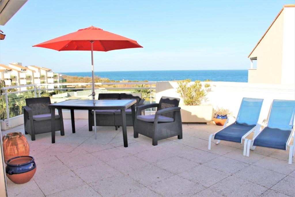 une terrasse avec une table, des chaises et un parasol dans l'établissement GOELETTES 311, à Saint-Cyprien