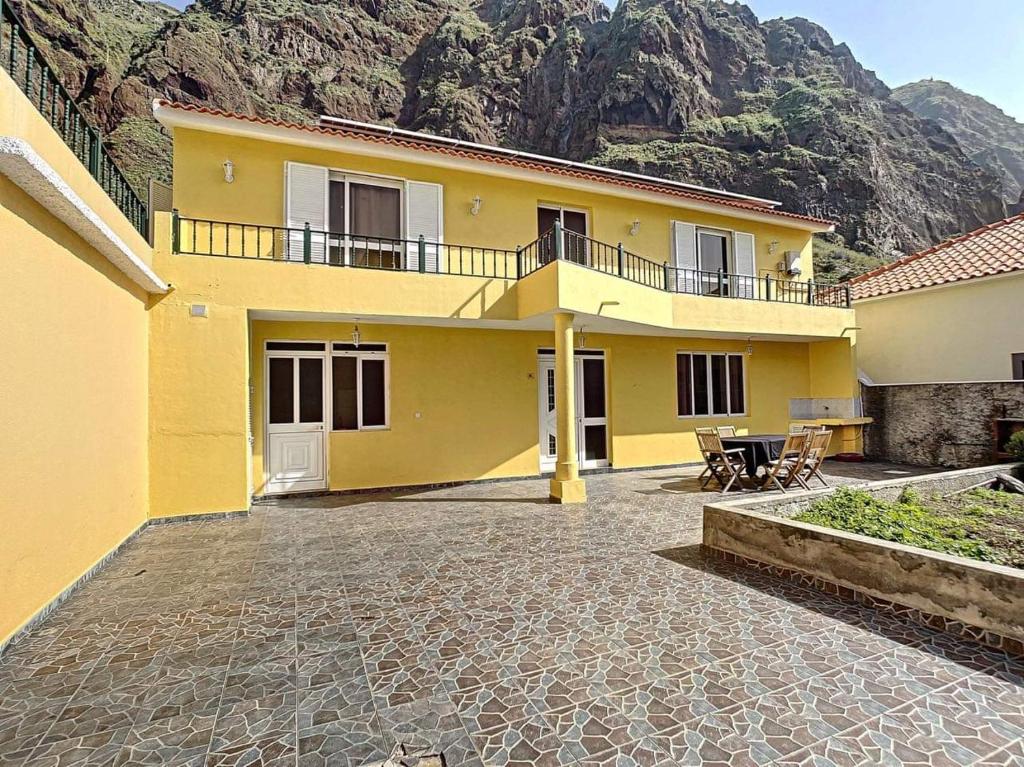 Casa amarilla con patio frente a una montaña en Vila Feliz, en Paul do Mar