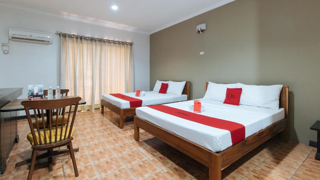 sypialnia z 2 łóżkami, stołem i biurkiem w obiekcie RedDoorz @ Balay Hiraya Apartment w mieście Tabao