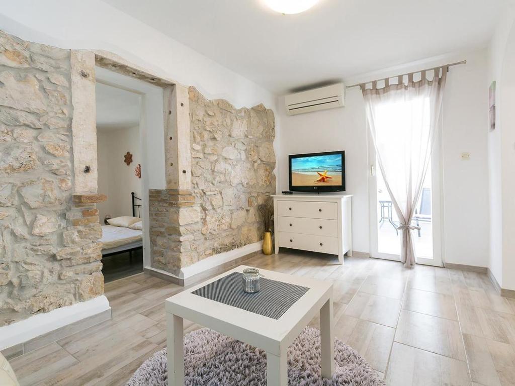 a living room with a tv and a stone wall at Ania Apartment in Poreč