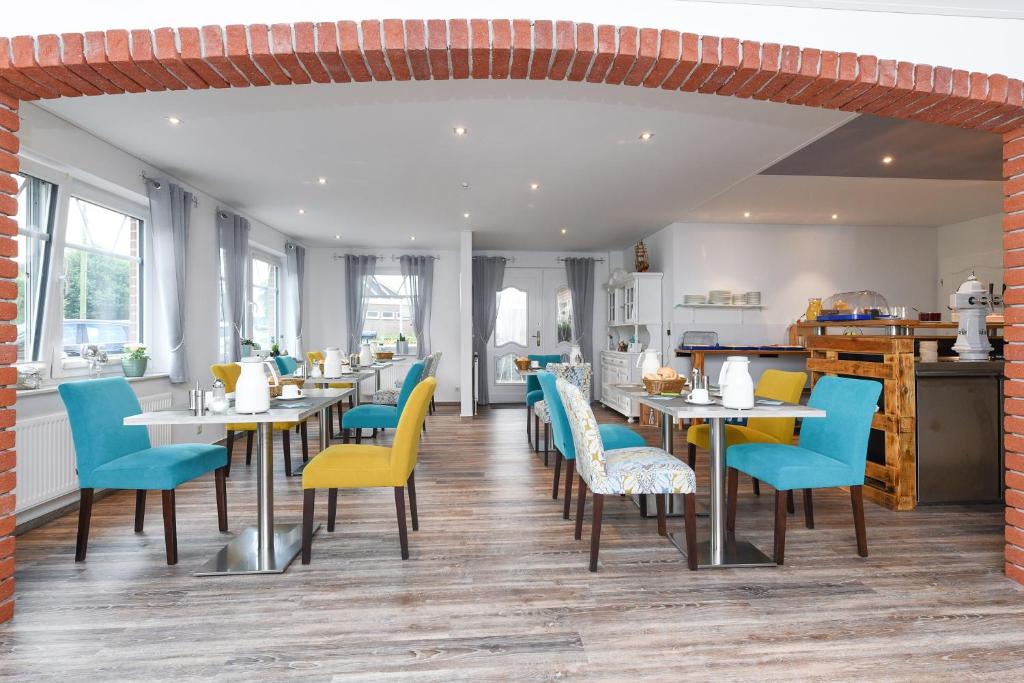 um restaurante com mesas e cadeiras azuis e amarelas em Hotel-Pension Janssen - Gästehaus Huus an't Deep em Neuharlingersiel