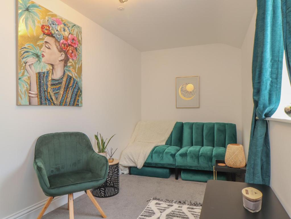 a living room with a green couch and a chair at Mews House in Camborne