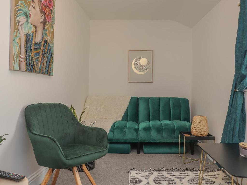 a living room with two green chairs and a table at Mews House in Camborne