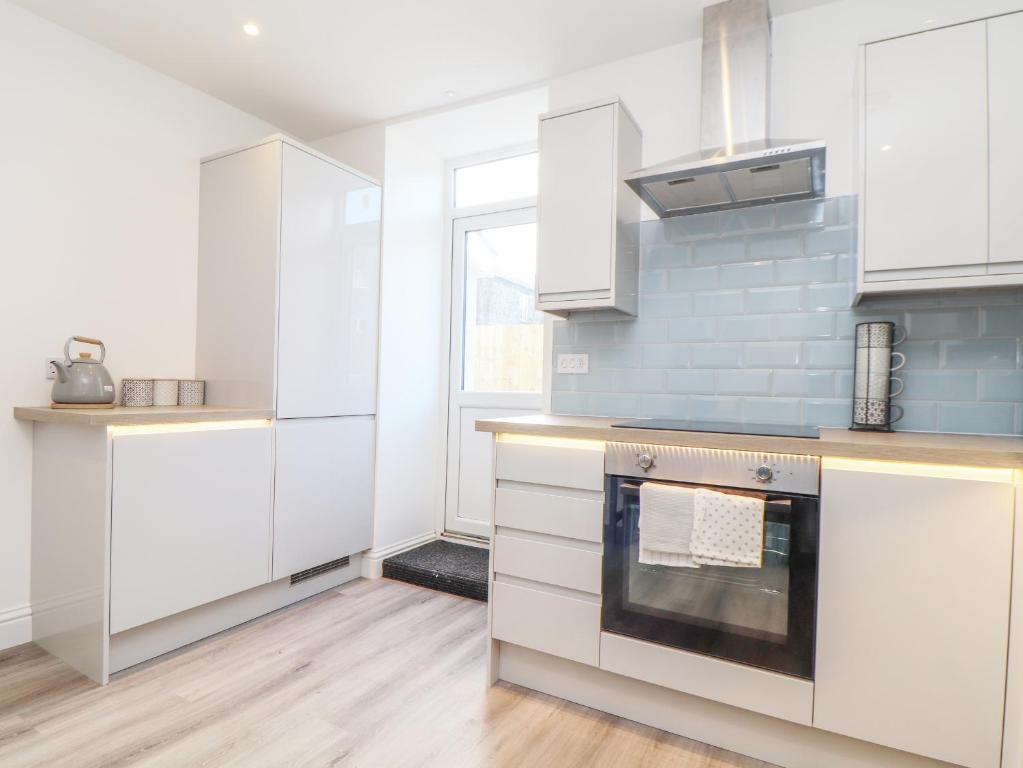a kitchen with white cabinets and a stove at Mews House in Camborne